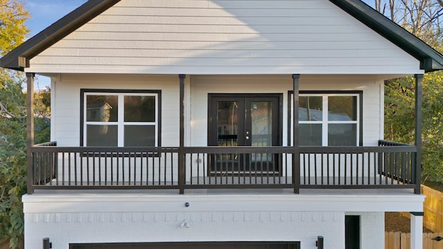 rear view of house with a balcony, french doors, and a garage