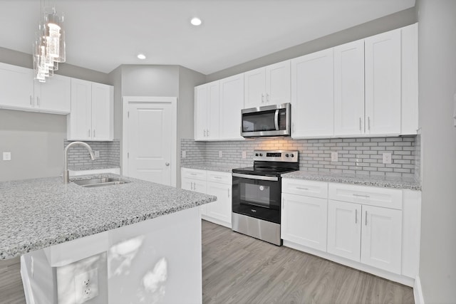 kitchen with sink, hanging light fixtures, light hardwood / wood-style flooring, white cabinets, and appliances with stainless steel finishes