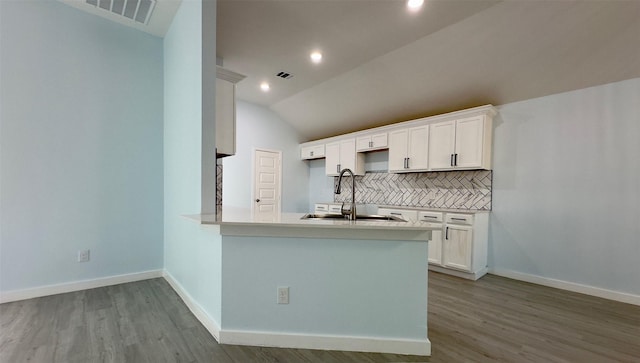 kitchen featuring white cabinets, lofted ceiling, tasteful backsplash, sink, and kitchen peninsula