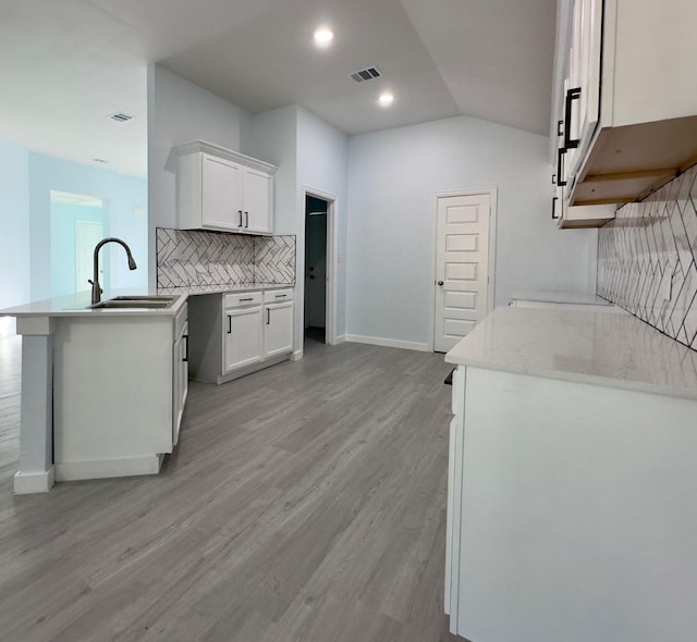 kitchen with sink, backsplash, white cabinets, and light hardwood / wood-style flooring