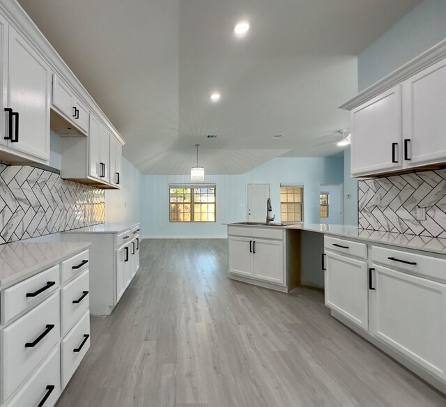 kitchen with sink, white cabinetry, decorative backsplash, and lofted ceiling