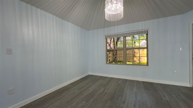 empty room featuring an inviting chandelier and dark hardwood / wood-style floors