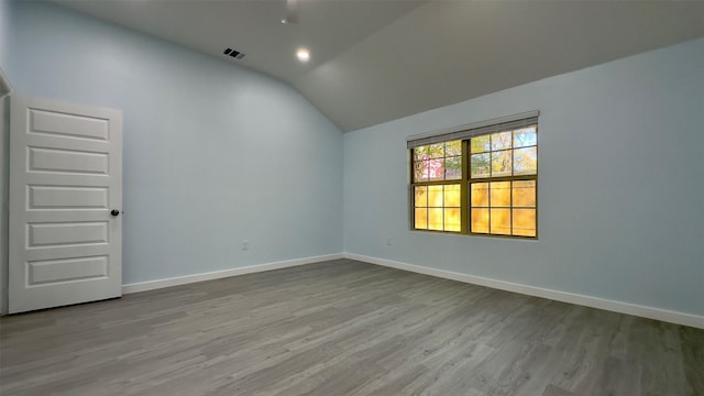 spare room featuring wood-type flooring and vaulted ceiling