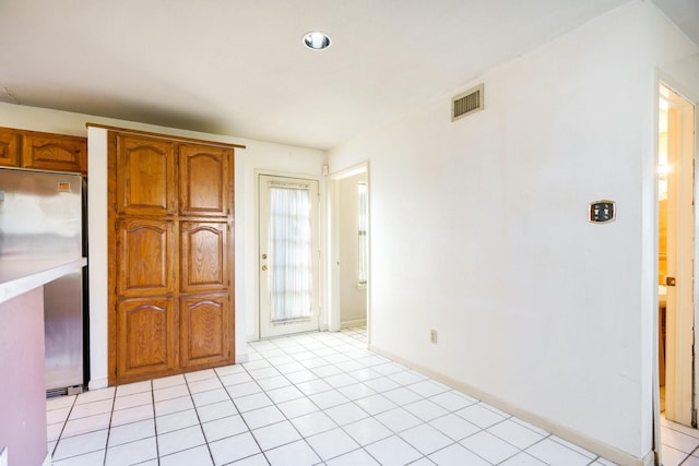 kitchen with light tile patterned flooring and stainless steel refrigerator