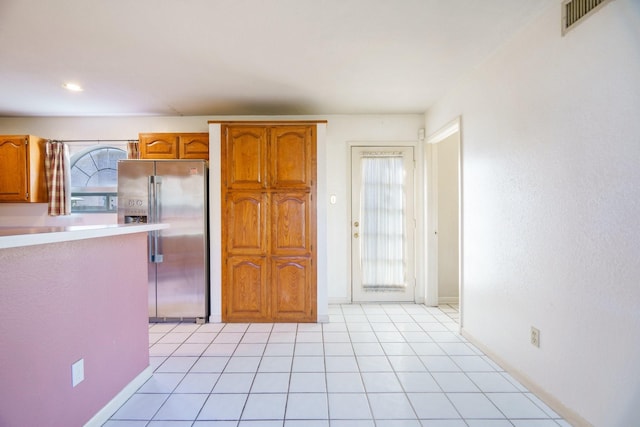 kitchen featuring plenty of natural light, light tile patterned flooring, and stainless steel fridge with ice dispenser