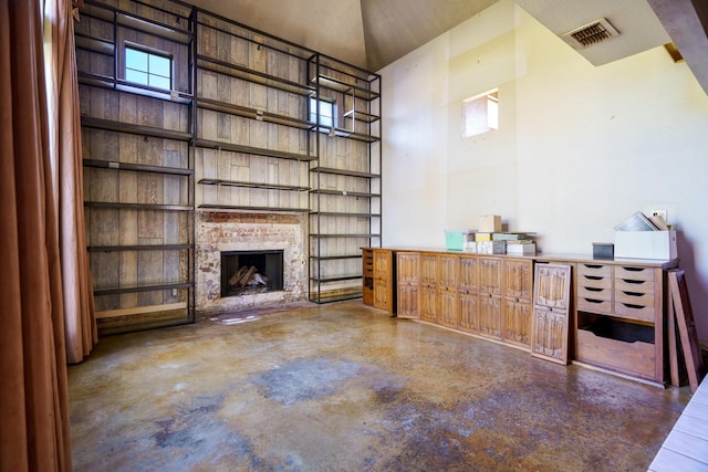 unfurnished living room featuring a towering ceiling and a brick fireplace