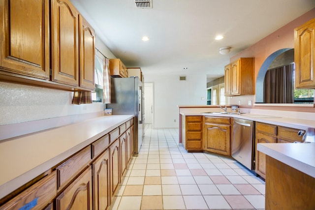 kitchen with light tile patterned flooring, stainless steel appliances, kitchen peninsula, and sink