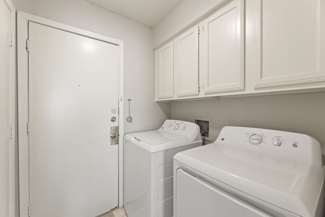 washroom with washing machine and dryer, cabinets, and a textured ceiling