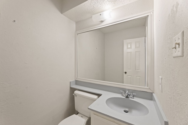 bathroom featuring vanity, a textured ceiling, and toilet