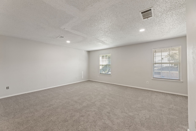 empty room with carpet floors and a textured ceiling