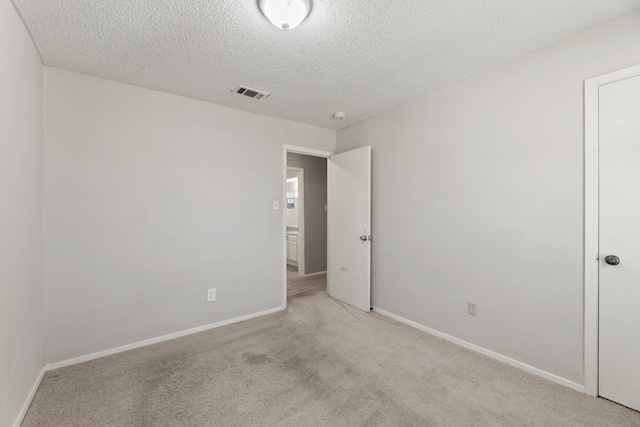 carpeted empty room featuring a textured ceiling