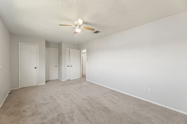 unfurnished bedroom with a textured ceiling, ceiling fan, and light carpet