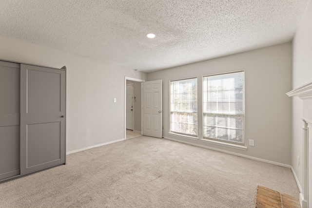 unfurnished bedroom with light colored carpet, a textured ceiling, and a closet