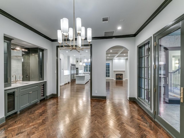 dining area with dark parquet flooring, ornamental molding, sink, a chandelier, and wine cooler