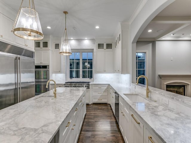 kitchen with sink, light stone counters, pendant lighting, white cabinets, and appliances with stainless steel finishes