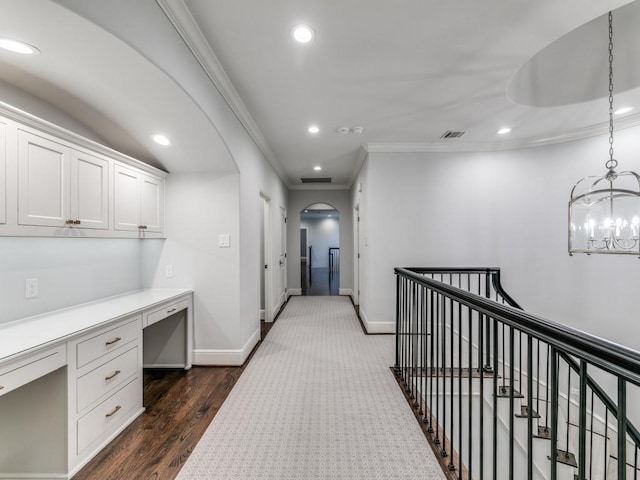 hallway featuring a notable chandelier, dark hardwood / wood-style flooring, and ornamental molding