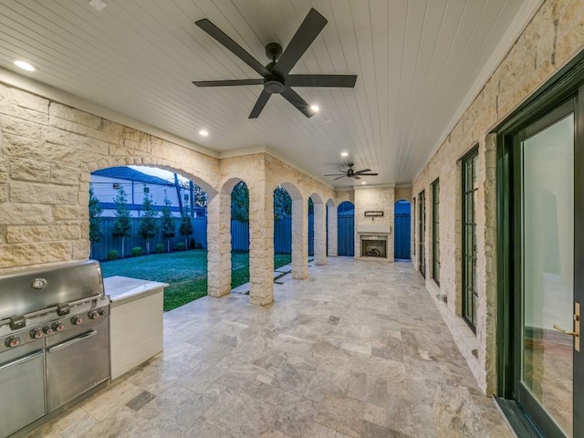 view of patio featuring an outdoor stone fireplace, area for grilling, and ceiling fan