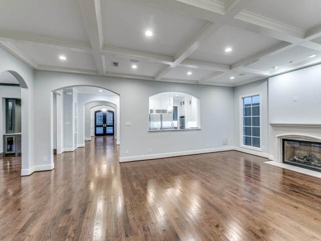 unfurnished living room featuring beam ceiling, crown molding, dark wood-type flooring, and coffered ceiling