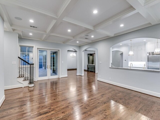 unfurnished living room with coffered ceiling, beam ceiling, wood-type flooring, and french doors