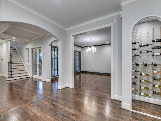 spare room featuring dark hardwood / wood-style floors, ornamental molding, and an inviting chandelier