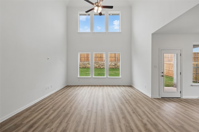 unfurnished living room with ceiling fan, a wealth of natural light, and wood finished floors