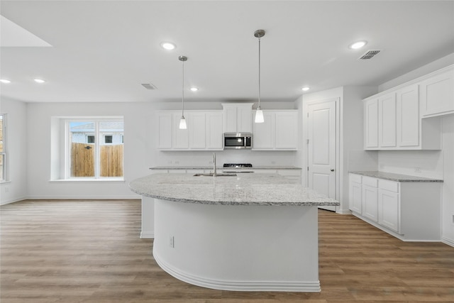 kitchen featuring a sink, baseboards, stainless steel microwave, and wood finished floors