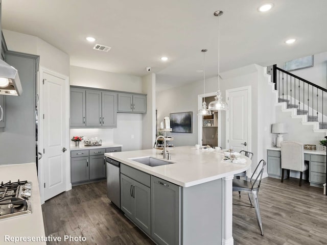 kitchen featuring a kitchen island with sink, hanging light fixtures, sink, dark hardwood / wood-style floors, and stainless steel appliances