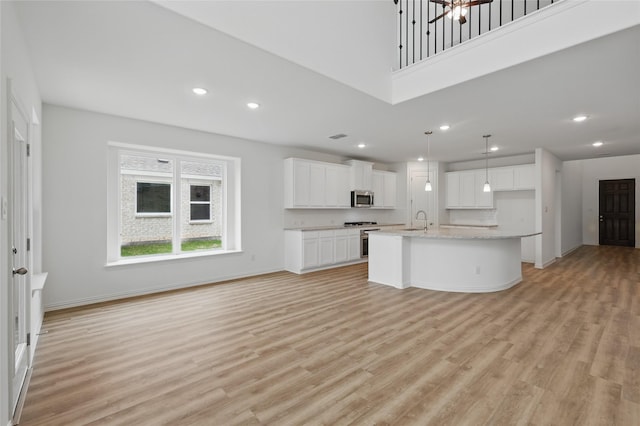 kitchen with light wood-type flooring, a sink, white cabinetry, and stainless steel microwave
