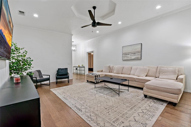 living room with hardwood / wood-style floors, ceiling fan with notable chandelier, and crown molding