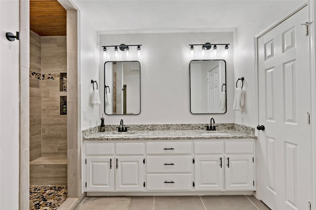 bathroom featuring tile patterned floors, vanity, and a tile shower