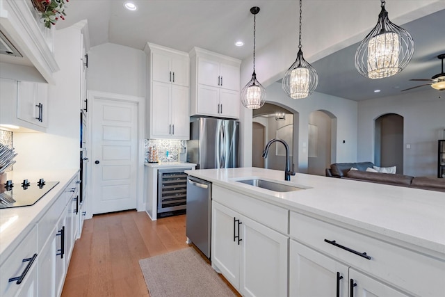 kitchen featuring stainless steel appliances, sink, white cabinetry, light hardwood / wood-style floors, and wine cooler