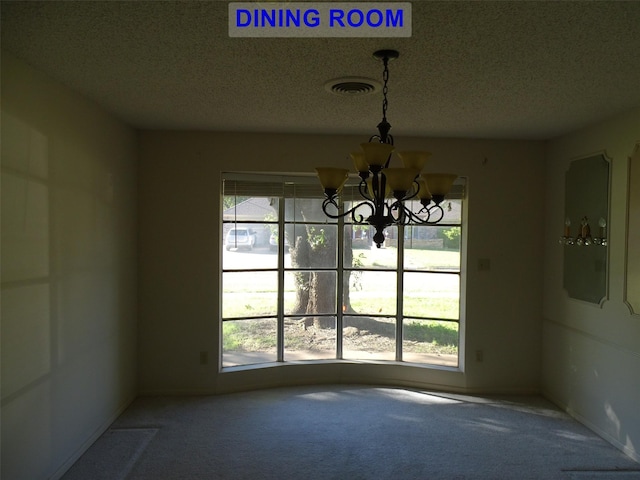 unfurnished dining area with carpet, a textured ceiling, and an inviting chandelier