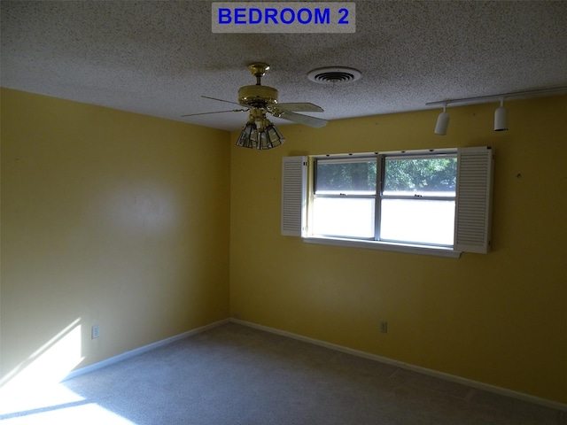 unfurnished room with carpet flooring, ceiling fan, and a textured ceiling