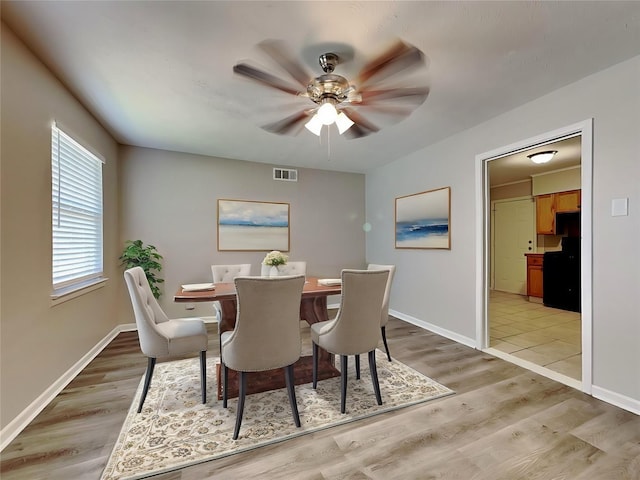 dining space with ceiling fan and light hardwood / wood-style flooring