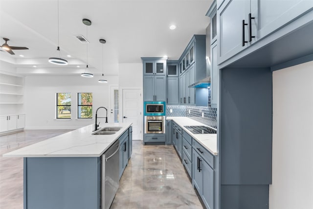 kitchen featuring sink, decorative backsplash, light stone countertops, appliances with stainless steel finishes, and decorative light fixtures