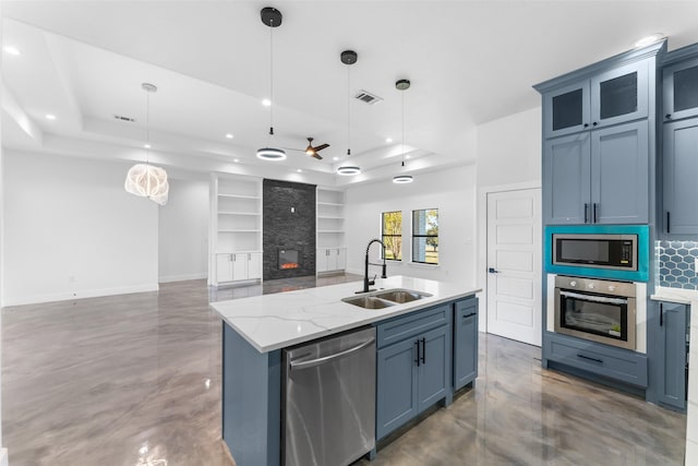 kitchen featuring pendant lighting, a center island with sink, a raised ceiling, sink, and stainless steel appliances