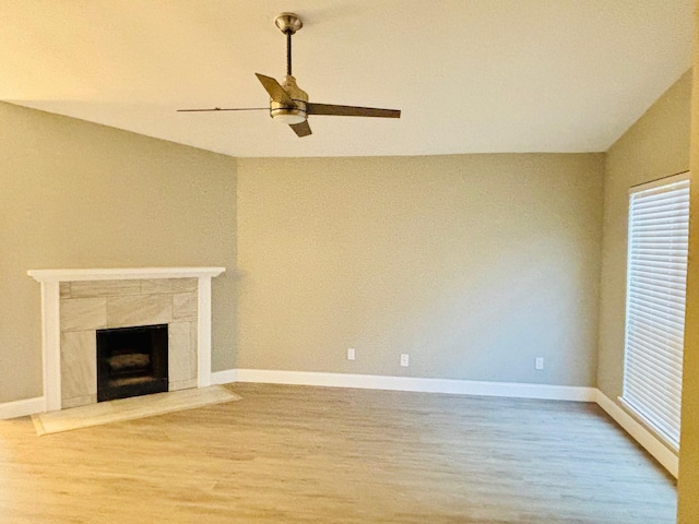 unfurnished living room featuring a tiled fireplace, ceiling fan, hardwood / wood-style floors, and vaulted ceiling