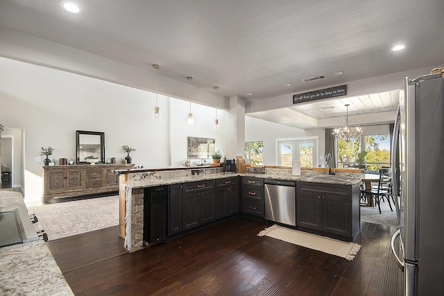 kitchen featuring light stone countertops, sink, dark hardwood / wood-style floors, decorative light fixtures, and appliances with stainless steel finishes