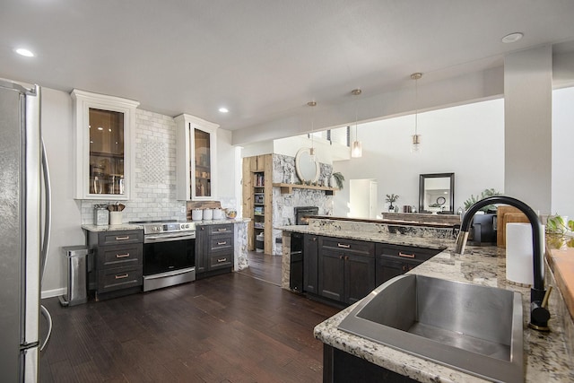 kitchen with sink, hanging light fixtures, dark wood-type flooring, white cabinets, and appliances with stainless steel finishes