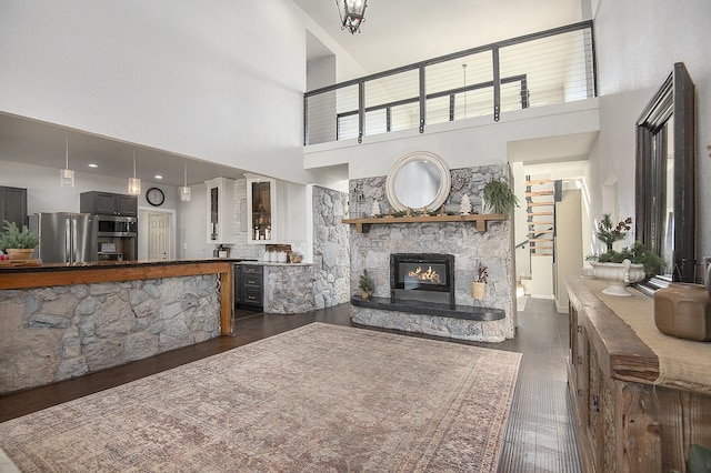 living room featuring dark hardwood / wood-style floors, a fireplace, and a high ceiling