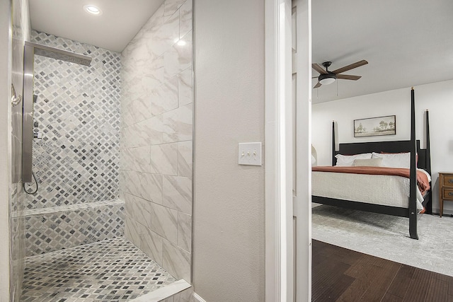 bathroom featuring ceiling fan, a tile shower, and wood-type flooring