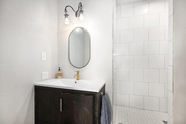 bathroom with a tile shower and vanity