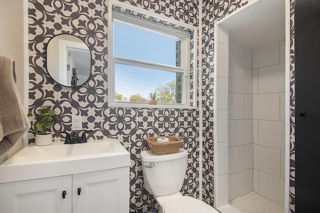 bathroom with tiled shower, vanity, and toilet