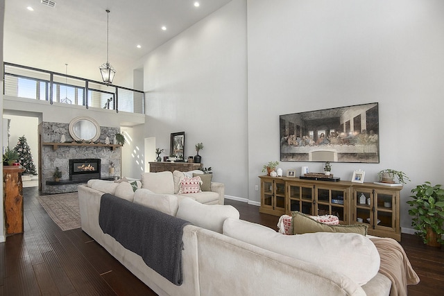 living room featuring dark hardwood / wood-style floors, a fireplace, and a high ceiling