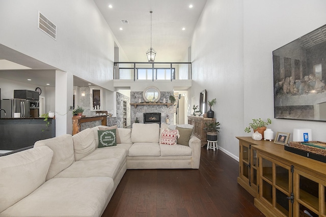 living room with a fireplace, dark hardwood / wood-style flooring, a towering ceiling, and a chandelier