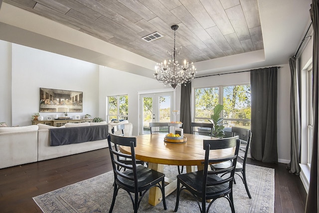 dining room featuring dark hardwood / wood-style floors, a tray ceiling, a chandelier, and french doors