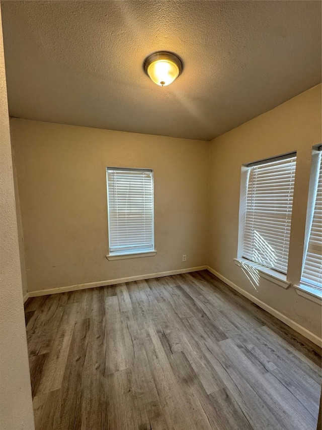 spare room featuring light hardwood / wood-style floors and a textured ceiling