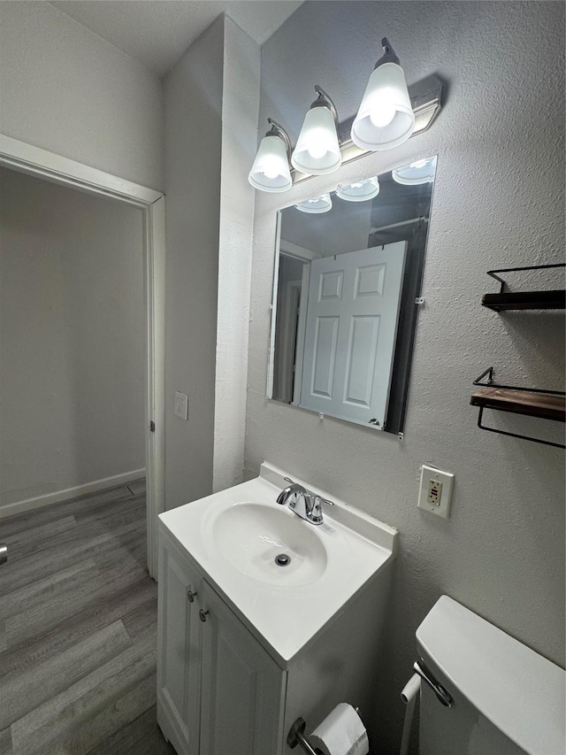 bathroom with wood-type flooring, vanity, and toilet