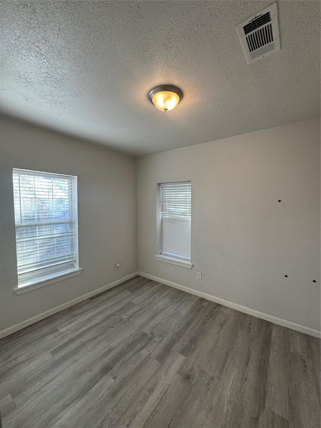 empty room featuring wood-type flooring and a textured ceiling