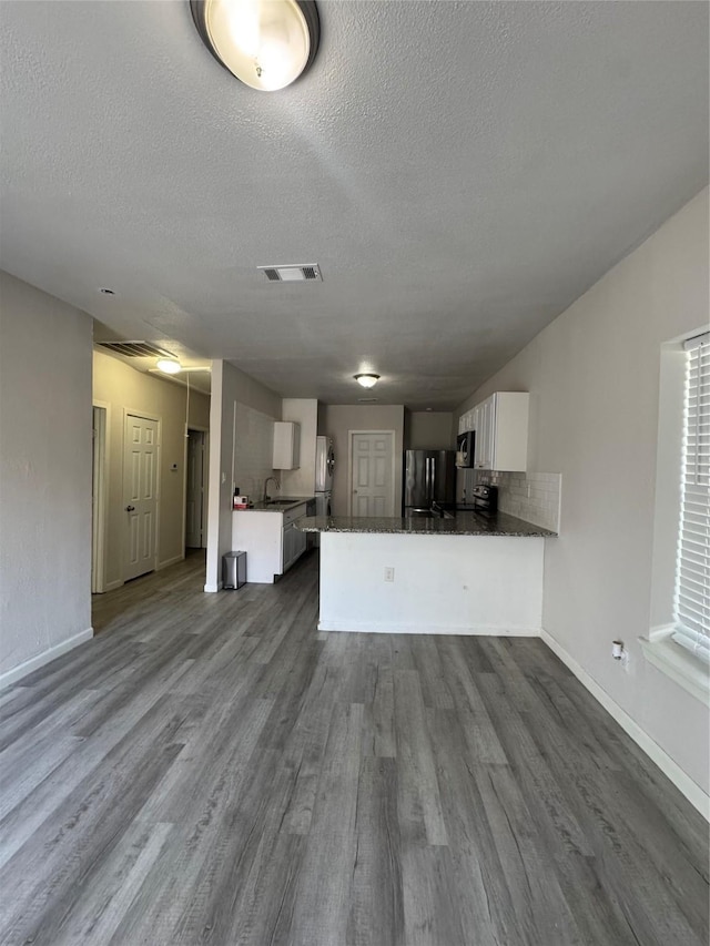 unfurnished living room featuring sink, a textured ceiling, and hardwood / wood-style flooring